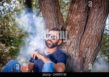 Brutaler Vape-Mann, der eine E-Zigarette raucht. Vape. Stockfoto