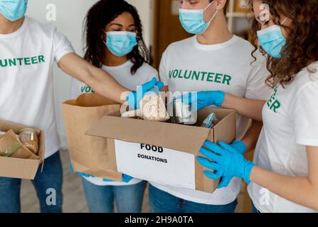 Internationale Gruppe junger Freiwilliger, die gespendete Lebensmittel in Schachteln sortieren, im Spendenzentrum der Wohltätigkeitsorganisation arbeiten, Nahaufnahme Stockfoto