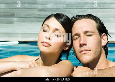 Mann und Frau im Schwimmbad genießen die Sonne, die Augen geschlossen. Stockfoto