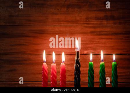 Happy Kwanzaa. Afroamerikanischer Feiertag. Sieben brennende Kerzen, rot, schwarz und grün, in Kinara-Kerzenhalter. Symbole des afrikanischen Erbes. Stockfoto