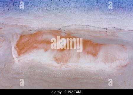 Frühmorgens wunderschöne, von oben nach unten geruhene Strandsandmuster, die wie ein schlafender Fuchs und eine Reihe von Fußabdrücken, die den Sand durchqueren, aussehen Stockfoto