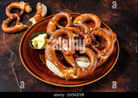 Frisch gebackene hausgemachte Brezel mit Salz auf einem rustikalen Teller. Dunkler Hintergrund. Draufsicht Stockfoto