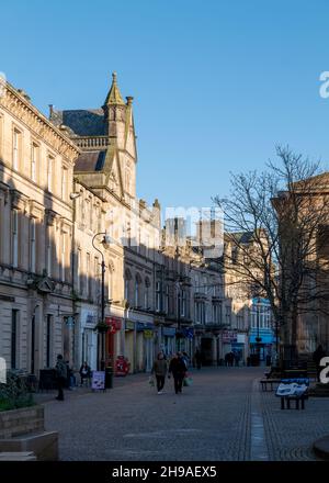 ELGIN, MORAY, SCHOTTLAND - 3. DEZEMBER 2021: Dies ist die sehr niedrige Sonne, die auf einige der Architektur von High Street, Elgin, Moray, Schottland scheint. Stockfoto