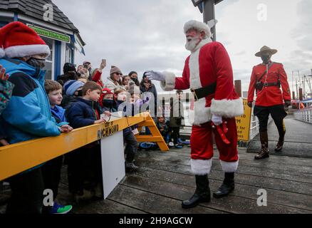 Richmond, Kanada. 5th Dez 2021. Am 5. Dezember 2021 interagiert ein Mann, der als Weihnachtsmann gekleidet ist, mit Kindern im Steveston Village Fisherman's Wharf in Richmond, British Columbia, Kanada. Die Veranstaltung der Ankunft des Weihnachtsmannes mit dem Boot startete hier am Sonntag die Weihnachtszeit. Quelle: Liang Sen/Xinhua/Alamy Live News Stockfoto