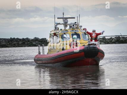 Richmond, Kanada. 5th Dez 2021. Ein Mann, der als Weihnachtsmann gekleidet ist, kommt am 5. Dezember 2021 mit dem Boot an der Steveston Village Fisherman's Wharf in Richmond, British Columbia, Kanada, an. Die Veranstaltung der Ankunft des Weihnachtsmannes mit dem Boot startete hier am Sonntag die Weihnachtszeit. Quelle: Liang Sen/Xinhua/Alamy Live News Stockfoto