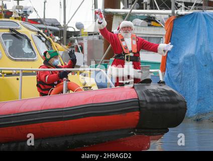 Richmond, Kanada. 5th Dez 2021. Ein Mann, der als Weihnachtsmann gekleidet ist, kommt am 5. Dezember 2021 mit dem Boot an der Steveston Village Fisherman's Wharf in Richmond, British Columbia, Kanada, an. Die Veranstaltung der Ankunft des Weihnachtsmannes mit dem Boot startete hier am Sonntag die Weihnachtszeit. Quelle: Liang Sen/Xinhua/Alamy Live News Stockfoto