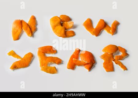 Unschärfe-Effekt Neujahrs-Wort, dargestellt durch trockene Orangenhaut auf einem isolierten weißen Hintergrund. Dekoration für Silvester, Konzept. Grußkarte. Text und DIY Stockfoto