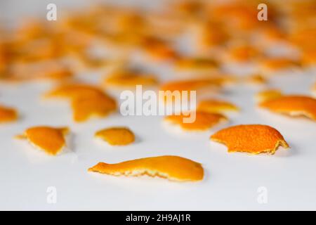 Unschärfe-Effekte verwischter weihnachtlicher Hintergrund aus den Schalen von Orange und Mandarine auf weißem Hintergrund. Viele kleine Stücke getrockneter Schale. Muster. Isoliert. Stockfoto