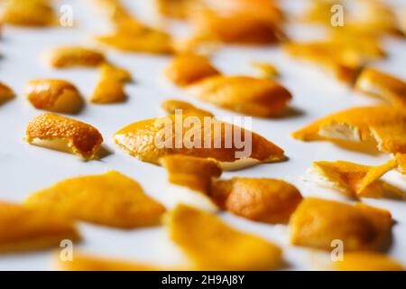 Unschärfe-Effekte im Weihnachtshintergrund. Nahaufnahme von trendigen Orangenschalen und Mandarinen auf weißem Hintergrund. Viele kleine Stücke getrockneter Schale. Muster. Isoliert. Stockfoto