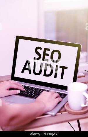 Textschild mit Seo Audit. Konzept Bedeutung Suchmaschinenoptimierung Validieren und Verifizieren Prozess beide Hände tippen auf Laptop neben Cup und Stockfoto