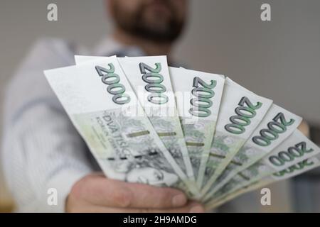 Tschechische Krone in nominalen zweitausendsten Banknoten 2000 CZK. Männer halten einen Fan von korun an der Hand. Tschechischer krimineller Geldkredit oder Finanzierungskonzept. Nahaufnahme Stockfoto
