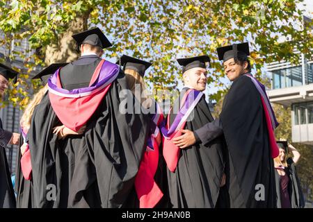 Absolventen der New University stehen bei der Zeremonie vor dem Queen Elizabeth II Centre London England für ein Fotoshooting an Stockfoto