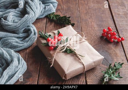 Geschenkbox mit Bastelpapier Draufsicht wis gause grau auf Holztisch verpackt. Geschenk für jeden Urlaub. Stockfoto