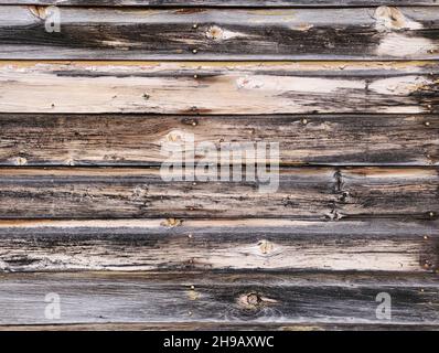 Nahaufnahme von verwitterten Holzverkettungen mit Holzmaserung und Ästen an der Außenseite eines Gebäudes. Stockfoto