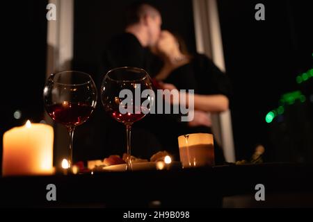 Valentinstag festliches Abendessen, brennende Kerzen und Weingläser auf dem Tisch, verliebten Paar küssen auf dem Hintergrund, Datum in der Wohnung Stockfoto