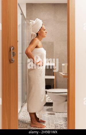 Volle Seitenansicht einer erwachsenen Frau, die mit Handtüchern eingewickelt ist. Stockfoto