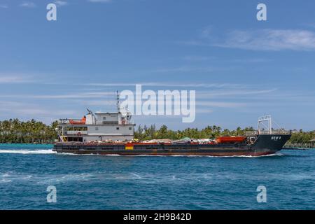 Nassau, Bahamas - 14. Mai 2019: Fähre New G segelt im Hafen von Nassau. Türkisfarbenes Wasser im Vordergrund. Uferlinie mit Palmen und blau bewölkten s Stockfoto