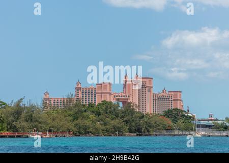 Nassau, Bahamas - 14. Mai 2019: Entfernte Aufnahme des Atlantis Resorts und Hotels auf Atlantis Paradise Island. Türkisfarbenes Wasser und Bäume im Vordergrund. Bl Stockfoto