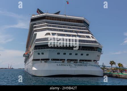 Nassau, Bahamas - 14. Mai 2019: Das Carnival Sunrise-Schiff dockte an der Prince George Wharf an. Blaue Anlegestellen, die zum Pier führen. Spitze des Trichters Stockfoto