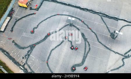 Luftaufnahme der Kart-Piloten, die die Kart-Spur in Schutzkleidung und Helm trangen oder gegeneinander antreten. Kart-Fahrtraining. Kart-Rennen Stockfoto