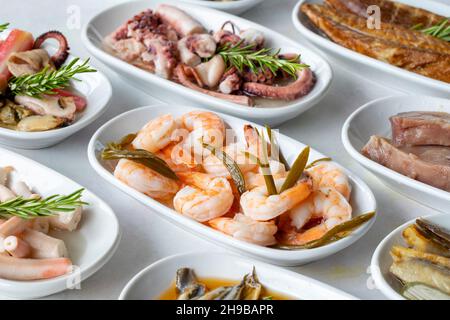 Auswahl an Fischgerichten. Meeresfrüchte auf einem Teller. Auf einem weißen Holzhintergrund. Selektiver Fokus Shrimp. Garnelen, Lakerda, Oktopus-Salat, Muscheln mit Marinade Stockfoto