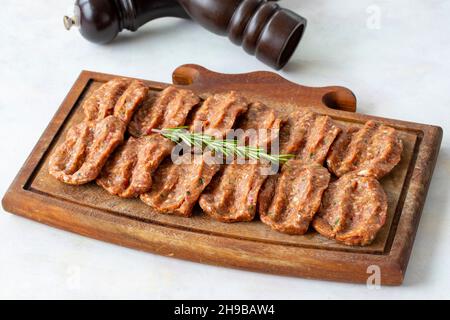 Würzige rohe Fleischbällchen auf Holzhintergrund. Türkische Fleischbällchen Stockfoto