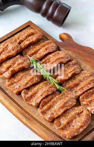 Würzige rohe Fleischbällchen auf Holzhintergrund. Türkische Fleischbällchen Stockfoto