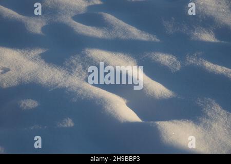 Bei sonnigem, frostigen Wetter ein Fragment einer verschneiten, hügeligen Oberfläche mit kleinen Gruben Stockfoto