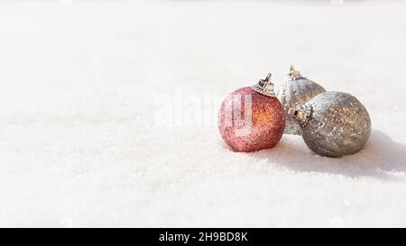 Weihnachtskugeln Schnee. Silberne und rosa glänzende Weihnachtsdekorationen liegen auf dem Schnee und funkeln. Das Konzept eines Urlaubs, Geschenke, Herzlichen Glückwunsch. Horiz Stockfoto
