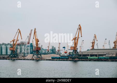 Bulk-Carrier-Schiff unter Ladung von Klinker Ladung Verladung durch Landkrane mit Greifern. Seehandel Hafentätigkeit. Bulk-Cargo-Terminal des Seehafens Stockfoto