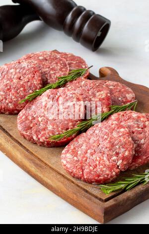 Rohe Rindfleisch-Burger-Patties auf Holzhintergrund. Stockfoto