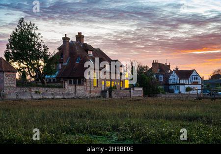 Große freistehende Häuser am Wasser bei Ebbe und im Abendlicht auf der anderen Seite des Bosham Quay / Harbour, Bosham Village, West Sussex, Großbritannien. Stockfoto