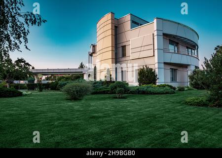 Luxus-Villa umgeben von Rasen mit Pflanzen und Blumen im Sommer Morgen Stockfoto
