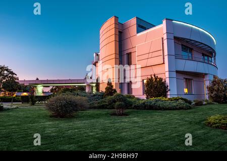 Gepflegter Rasen, Wacholderplantagen und Blumenbeete rund um die Luxusvilla am Sommerabend Stockfoto