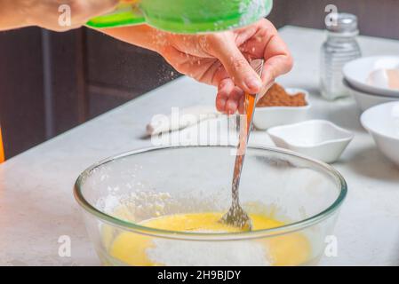 Mehl wird mit den Zutaten in den Becher gegeben Stockfoto