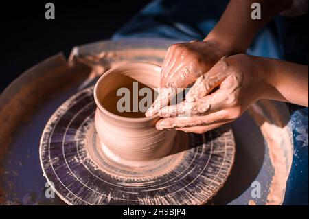 Frauen Hände. Potter bei der Arbeit. Gerichte zubereiten. Potter's Rad. Schmutzige Hände im Ton und im Töpferrad mit dem Produkt. Erstellung. Arbeiten Stockfoto