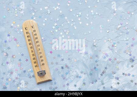 Thermometer zeigt niedrige plus Temperatur und Weihnachtsdekoration auf weiß und blau mit Sternen festlichen Hintergrund. Winter- und Urlaubswetterkonzept, Platz kopieren Stockfoto