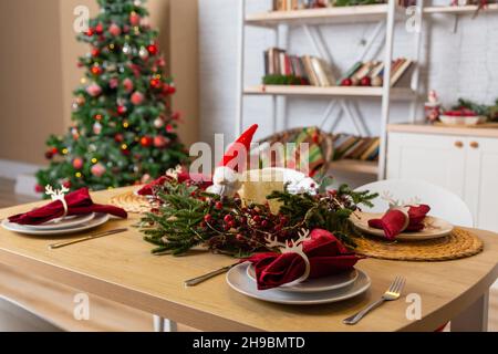 Schöner Tisch mit weihnachtlicher Einrichtung im Wohnzimmer. Feiern. Platz für Weihnachtsessen. Weihnachtsdekoration. Einrichtung. Stockfoto