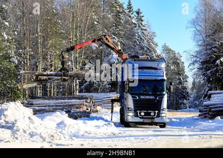 Das Verladen von Holzstämmen auf silbernen Scania R730 LKW zog im Winter mit Kran am Waldrand Holzanhänger. Salo, Finnland. 11. Februar 2021 Stockfoto