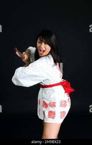 Junge asiatische Frau mit einem Bokken (ein japanisches Holzschwert, das zum Üben verwendet wird) Stockfoto