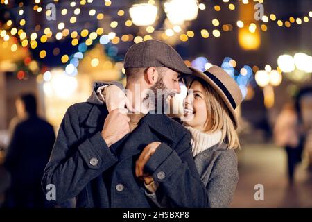 Verliebter Weihnachtsmann umarmt sich an Weihnachten auf der Straße. Ein amoröses junges Paar steht am Heiligabend auf der Straße, umarmt und umarmt Stockfoto