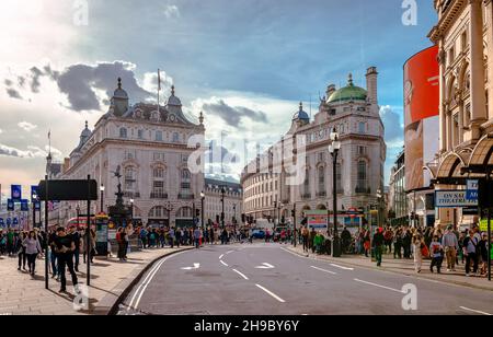 Die Menschen genießen einen sonnigen Nachmittag im Piccadilly Circus. Der Zirkus ist in der Tat eine Straßenkreuzung, die 1819 erbaut wurde, um die Regent Street mit Piccadilly zu verbinden. Stockfoto