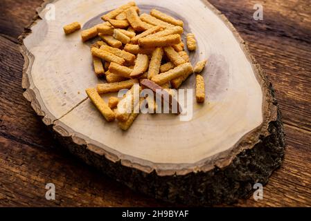 Weizen gebratene Croutons auf einem hölzernen Hintergrund. Snack auf einer Platte aus einem Holzschnitt. Stockfoto