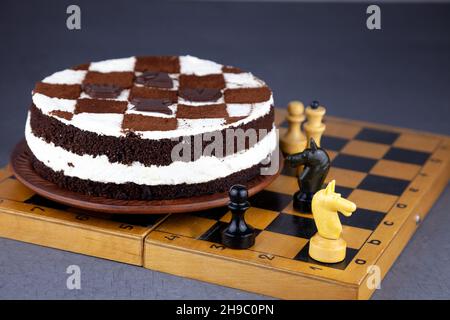 Biskuitkuchen mit Buttercreme. Kuchen in Form eines Schachbretts. Ein Geschenk für den Tag eines Schachspielers. Kuchen mit Schokoladenkuchen und weißem Pudding. Appetitliches Dessert. Stockfoto