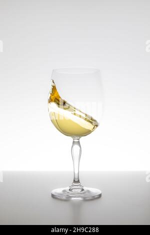 Weißwein wirbelt im Glas auf weißem Hintergrund Stockfoto