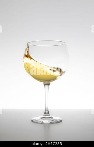 Weißwein wirbelt im Glas auf weißem Hintergrund Stockfoto