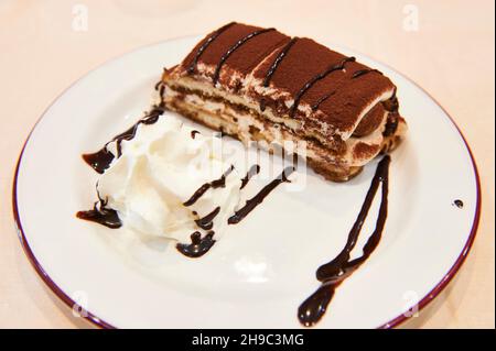 Tiramisu über weißem Gericht mit Creme und Schokolade, italienisches Dessert. Ansicht schließen Stockfoto