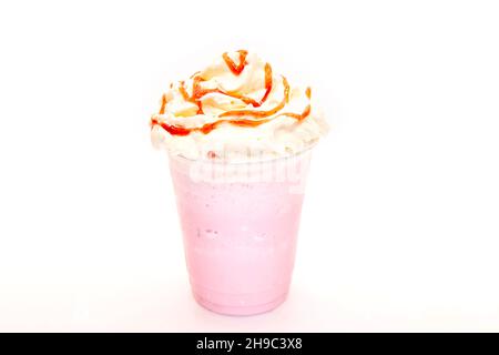 Erdbeermilch-Shake mit Sirup beträufelt auf Schlagsahne in einem Einweg-Plastikbecher. Stockfoto