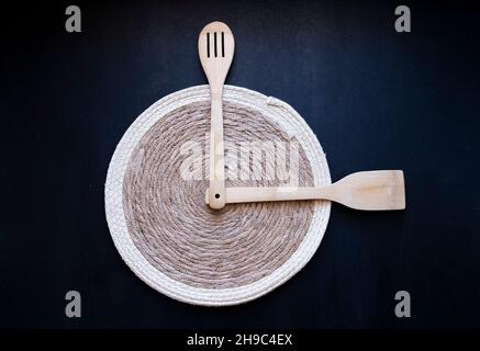 Holzlöffel und Spatel Uhr Idee auf einem Bambus serviert mit, Abendessen, Mittag-oder Frühstückszeit, Stroh Plaid Platzset auf isolierten schwarzen Hintergrund Stockfoto