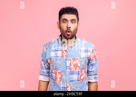 Porträt eines aufgeregten lustigen Mannes in einem blauen Hemd im Casual-Stil mit Puffellippen und großen, verblüfften Augen, überrascht und albern in der Kamera, wunderte sich über den Ausdruck. Innenaufnahme des Studios isoliert auf rosa Hintergrund. Stockfoto